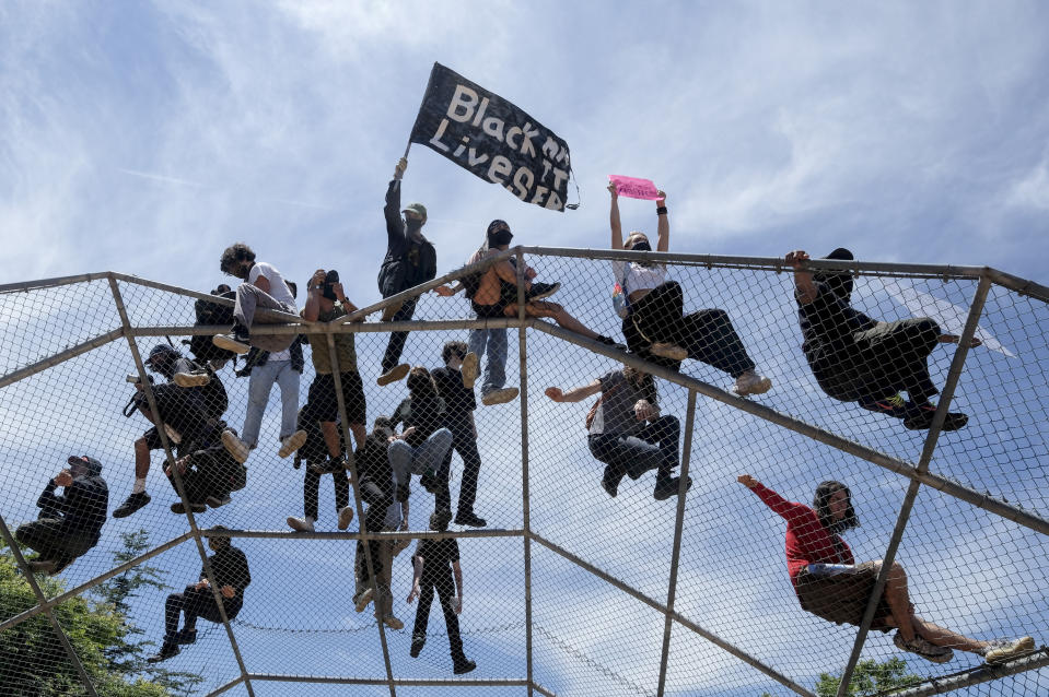 Gente sobre una estructura de bateo durante una protesta por la muerte de George Floyd en Los Ángeles, el sáado 30 de mayo de 2020. (AP Foto/Ringo H.W. Chiu)