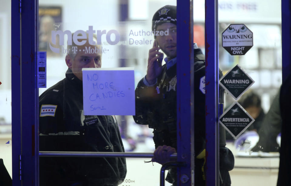 A police supervisor and officer stand inside a cell phone store in the 3700 block of West 26th Street, where a 7-year-old girl was shot while trick-or-treating Thursday, Oct. 31, 2019, in Chicago. A 7-year-old girl out trick-or-treating in a bumblebee outfit was critically injured Thursday night during a shooting on Chicago's West Side. (John J. Kim/Chicago Tribune via AP)