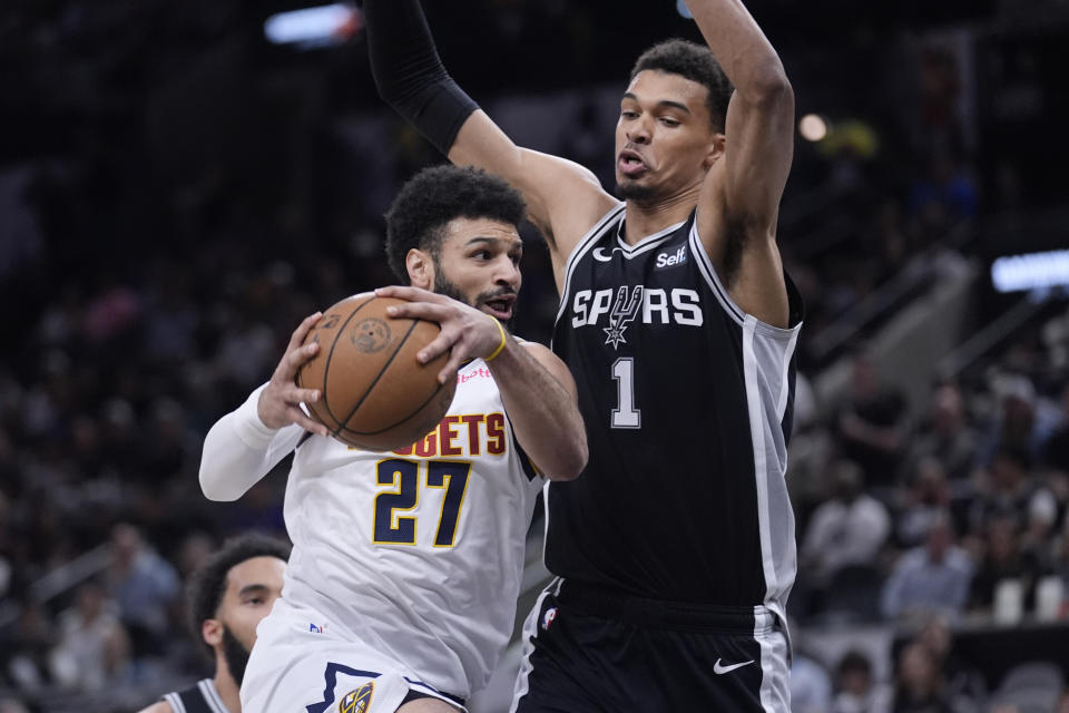 Denver Nuggets guard Jamal Murray (27) drives to the basket against San Antonio Spurs center Victor Wembanyama (1) during the first half of an NBA basketball game in San Antonio, Friday, April 12, 2024. (AP Photo/Eric Gay)