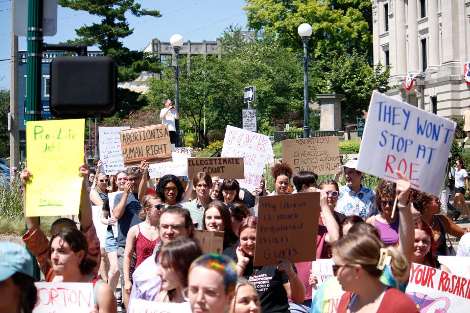 Protestors hoist their signs June 27 while walking up College Avenue to Planned Parenthood and the Women's Care Center.