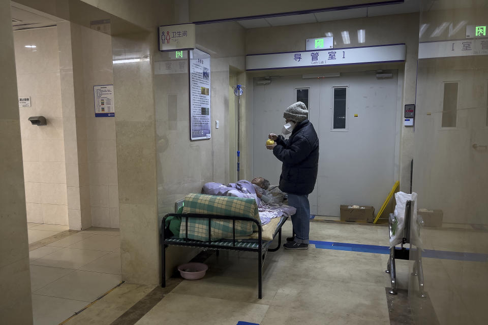 A woman attends to her elderly relative at a corridor of the emergency ward to receive intravenous drips at a hospital in Beijing, Thursday, Jan. 5, 2023. Patients, most of them elderly, are lying on stretchers in hallways and taking oxygen while sitting in wheelchairs as COVID-19 surges in China's capital Beijing. (AP Photo/Andy Wong)
