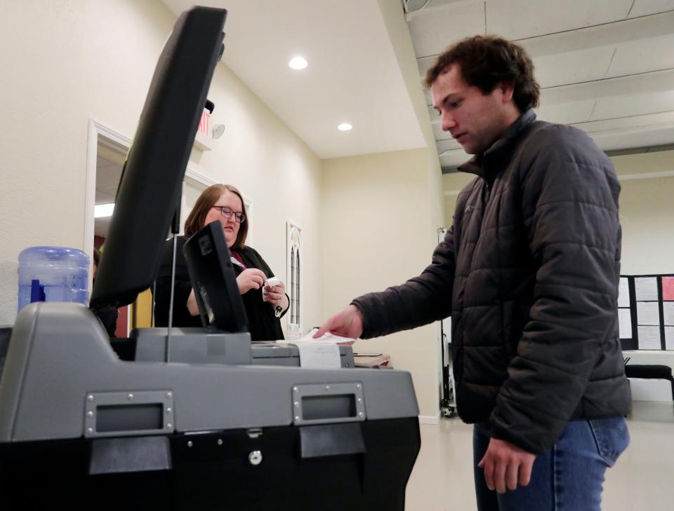 Poll worker Alicia Haugen, left, observes Zachary Dawidowach place his ballot into the tabulator at the Open Bible Baptist Church poll, Tuesday, April 4, 2023, in Manitowoc, Wis.