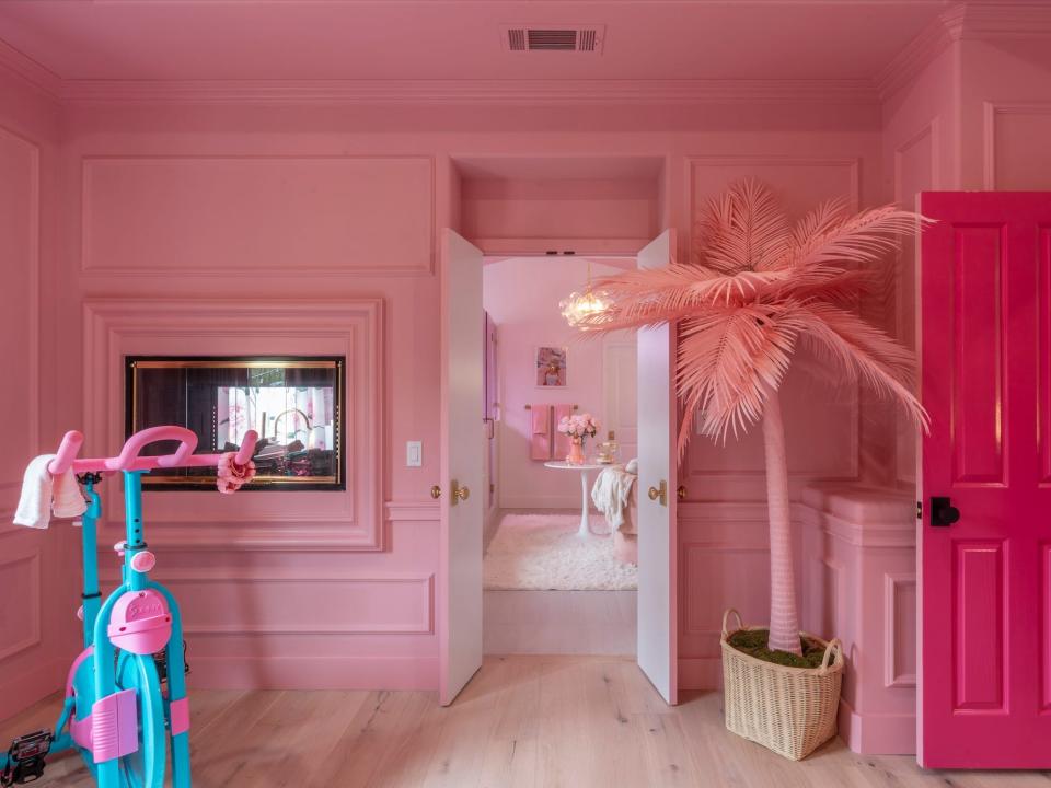 A pink bedroom with a fireplace on the wall, a pink tree, and an exercise bike.