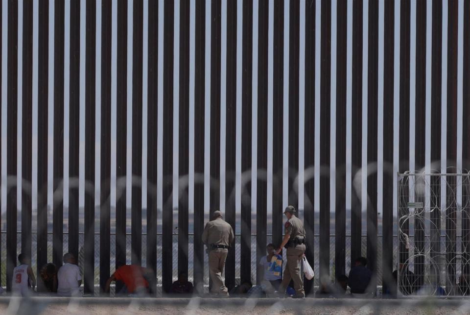 PHOTO: Migrants seeking asylum in the United States are watched by Texas agents next to the border wall, June 5, 2024, in El Paso, Texas. (Herika Martinez/AFP via Getty Images)