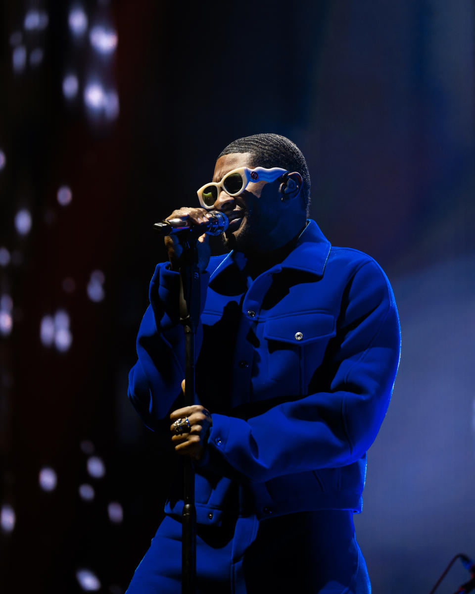 Usher performing at Dreamville Music Festival, wearing a blue jacket.
