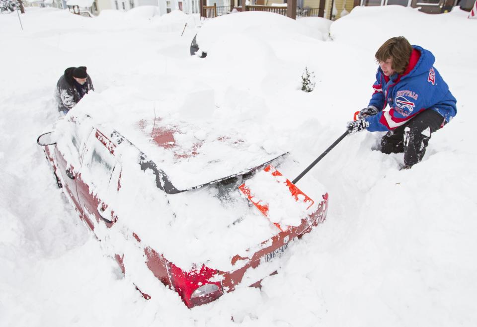 Lori and Bob Weishaar, shovel snow from around their vehicle following an autumn storm in Buffalo