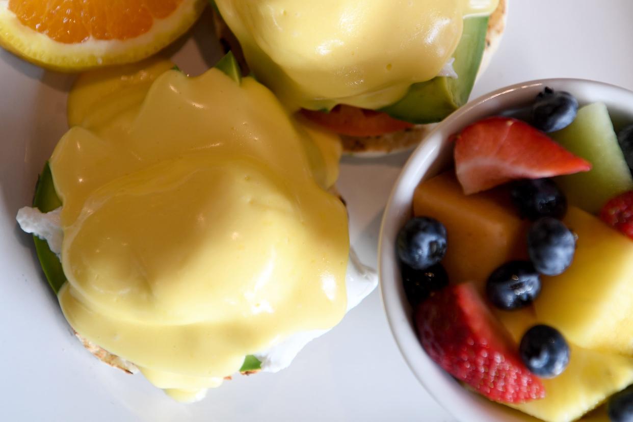 The Cali Benedict at Famous Toastery is poached eggs, avocado and tomato on an English muffin covered with house-made Hollandaise. Shown here with a side of fresh fruit. 