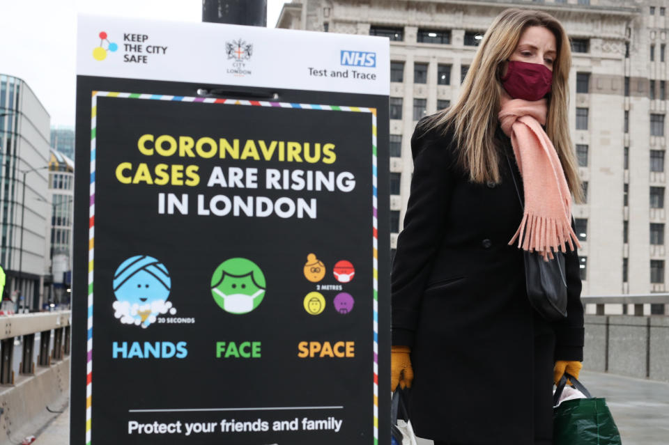 A woman walks past a coronavirus information sign on London Bridge, the morning after Prime Minister Boris Johnson set out further measures as part of a lockdown in England in a bid to halt the spread of coronavirus.
