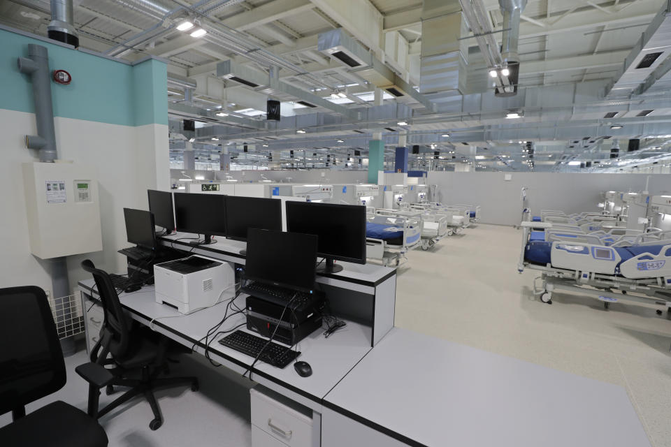 A desk with computer screens and new beds sit in the empty Isabel Zendal new hospital during the official opening in Madrid, Spain, Tuesday, Dec. 1, 2020. Authorities in Madrid are holding a ceremony to open part of a 1,000-bed hospital for emergencies that critics say is no more than a vanity project, a building with beds not ready to receive patients and unnecessary now that contagion and hospitalizations are waning. Spain has officially logged 1.6 million infections and over 45,000 deaths confirmed for COVID-19 since the beginning of the year. (AP Photo/Paul White)