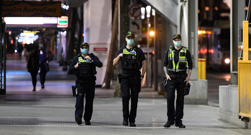 Three police officers, wearing masks, shown patrolling Melbourne streets. Source: AAP