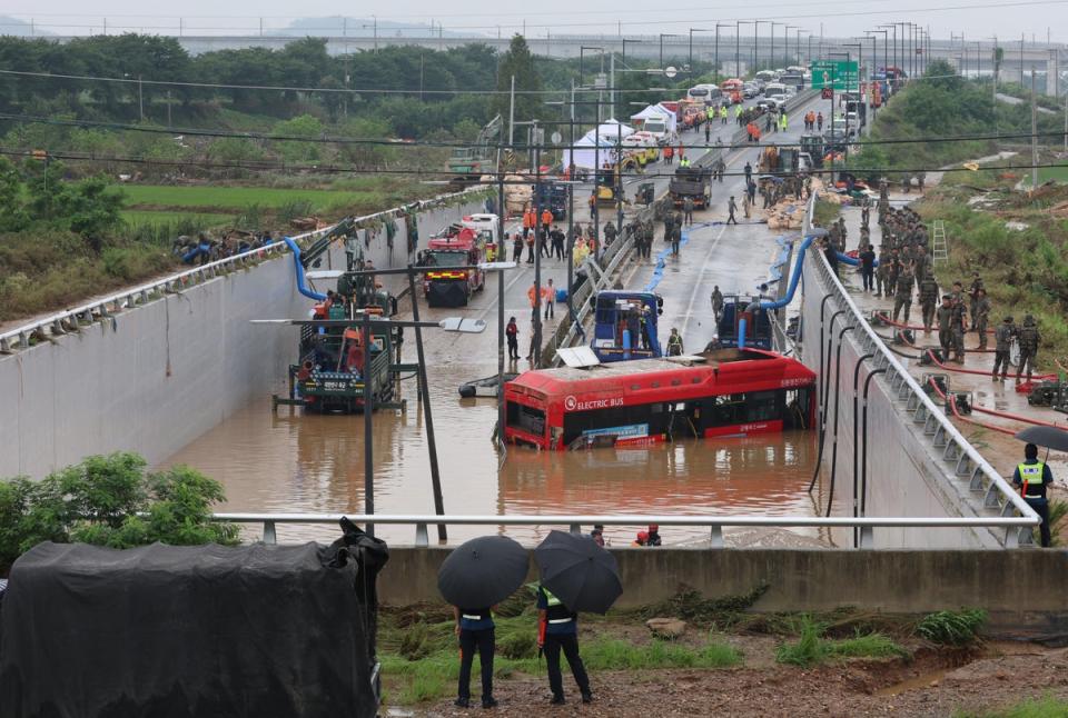 South Korean rescue workers search for missing persons along a deluged road leading to a tunnel in Cheongju (YONHAP/AFP via Getty Images)