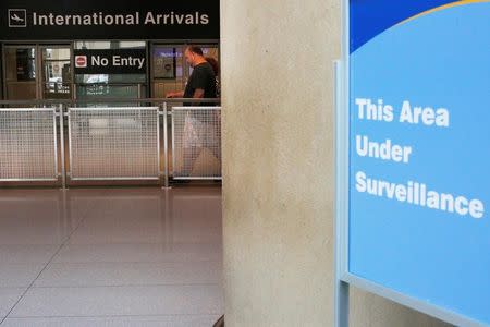 FILE PHOTO: A sign warns of surveillance at the International Arrival area, on the day that U.S. President Donald Trump's limited travel ban, approved by the U.S. Supreme Court, goes into effect, at Logan Airport in Boston, Massachusetts, U.S., June 29, 2017. REUTERS/Brian Snyder