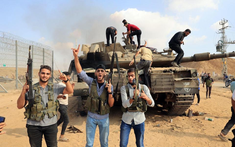 Palestinians take control of an Israeli tank after crossing the border fence with Israel from Khan Yunis in the southern Gaza Strip