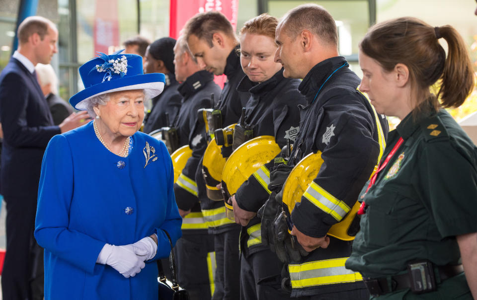 queen elizabeth in blue hat and blue coat with prince william in background, Queen Elizabeth II and Prince William meet with firefighters and paramedics during an event for the Grenfell Tower disaster on June 16, 2017. (Photo via Dominic Lipinski/PA Wire/Getty Images)