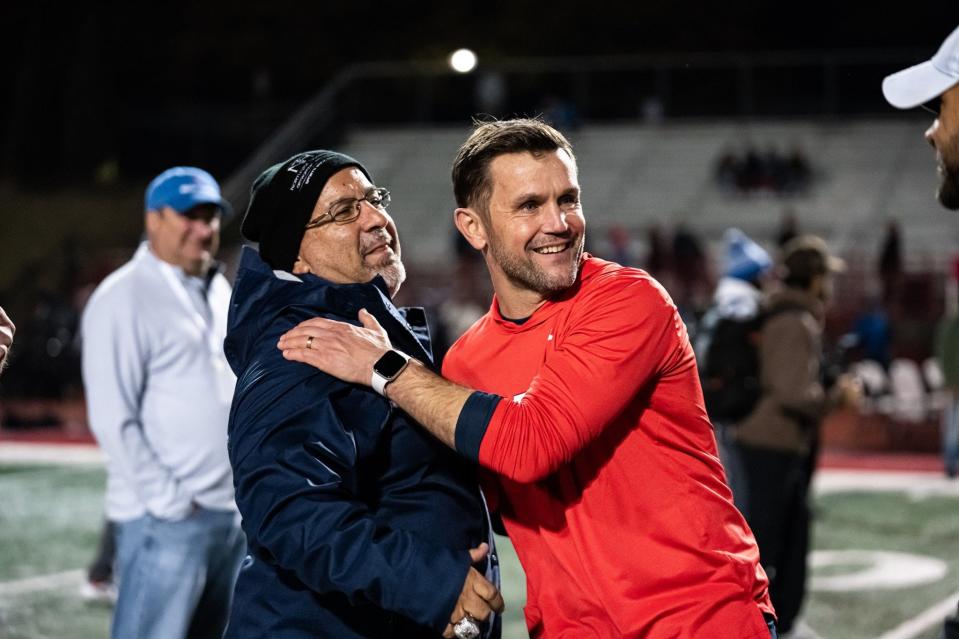 Former Milton head football coach Adam Clack (red) talks with Milton athletic director Gary Sylvestri after a Milton High School football game.