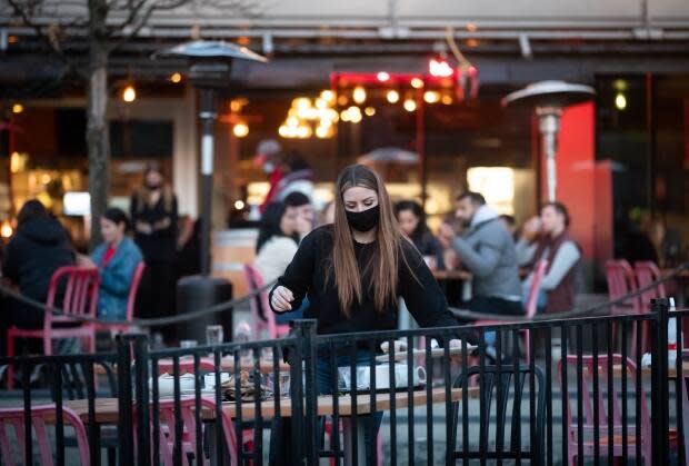 A server clears a table on a patio at a restaurant in Vancouver.