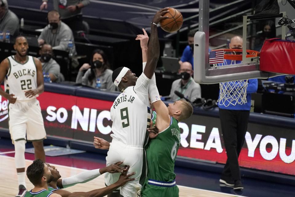 Milwaukee Bucks center Bobby Portis (9) attempts to dunk over Dallas Mavericks center Kristaps Porzingis, right, in the first half of an NBA basketball game in Dallas, Thursday, April 8, 2021. (AP Photo/Tony Gutierrez)