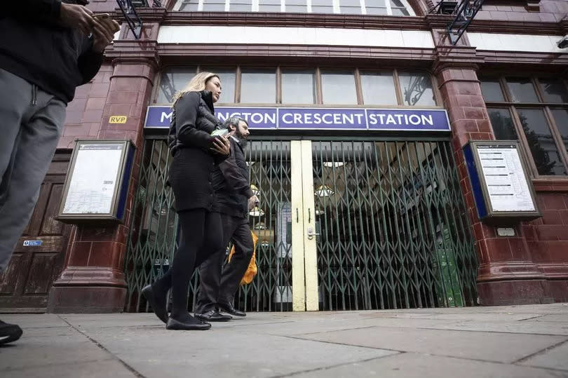 People walk past a Tube station with its metal gates closed