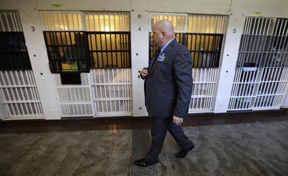 In this Nov. 18, 2013 photo, warden Nick Ludwick walks past an inmate in his cell at the Iowa State Penitentiary in Fort Madison, Iowa. The penitentiary, the oldest in use west of the Mississippi River with a history dating back to 1839, is set to close when a $130 million replacement opens down the road next year. (AP Photo/Charlie Neibergall)