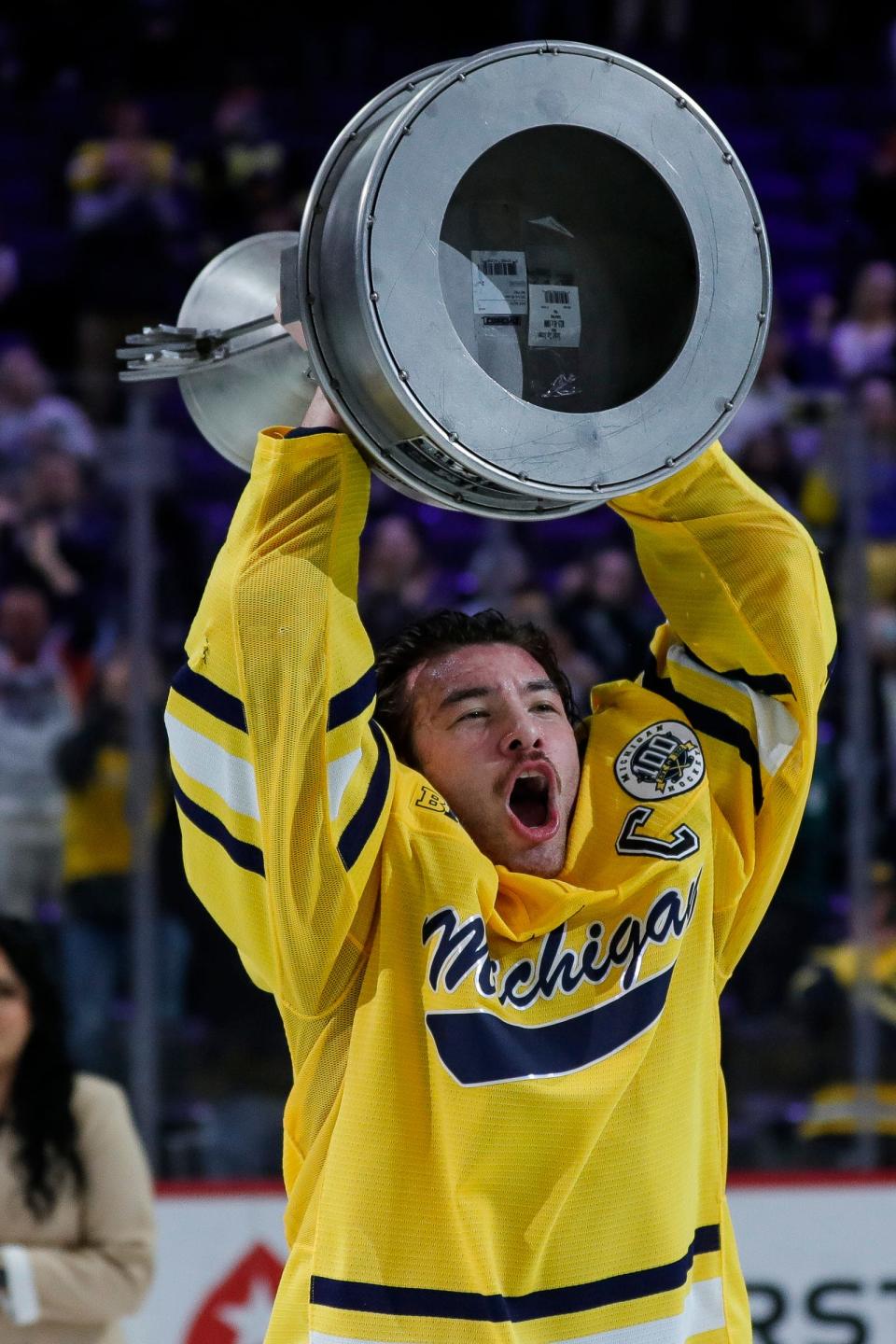 Michigan captin Nolan Moyle (27) lifts up the Iron D trophy to celebrate a 4-3 overtime win against Michigan State of the "Duel in the D" at Little Caesars Arena in Detroit on Saturday, Feb. 11, 2023.