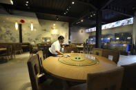 A worker cleans a table in an empty seafood restaurant on the popular tourist island of Bali, Indonesia on Wednesday, Jan. 18, 2023. A hoped-for boom in Chinese tourism in Asia over next week's Lunar New Year holidays looks set to be more of a blip as most travelers opt to stay inside China if they go anywhere. (AP Photo/Firdia Lisnawati)