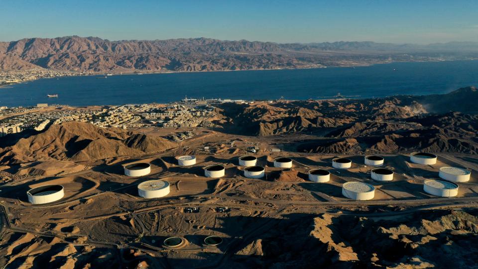 This picture taken on February 10, 2021 shows an aerial view of (foreground) oil storage containers of the Eilat Ashkelon Pipeline Company (EAPC) in the mountains near Israel's Red Sea port city of Eilat, and (background) the Jordanian coastline south of Aqaba. - Israeli environmentalists are warning that the UAE-Israeli deal to bring Emirati crude oil by tanker to a pipeline in Eilat threatens unique Red Sea coral reefs and could lead to 