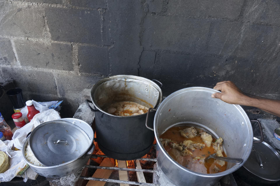 Migrantes de Colombia cocinan un plato que llaman "pollo americano" para venderlo a los otros 3.000 migrantes hacinados en tiendas de campaña dentro del albergue Senda de Vida 2 en Reynosa, México, el 15 de diciembre de 2022. El albergue, el segundo fundado por un pastor evangélico en esta ciudad fronteriza, alberga a migrantes de Haití, Centroamérica y América del Sur en tiendas de campaña montadas sobre cemento o grava áspera, brindando atención básica, pero especialmente seguridad ante los cárteles que se aprovechan de los migrantes que quedan afuera. (AP Foto/Giovanna Dell'Orto)