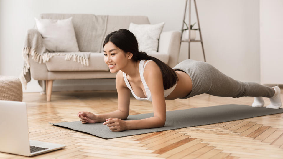 Online Training. Girl Exercising at Home, Doing Plank and Watching Videos on Laptop