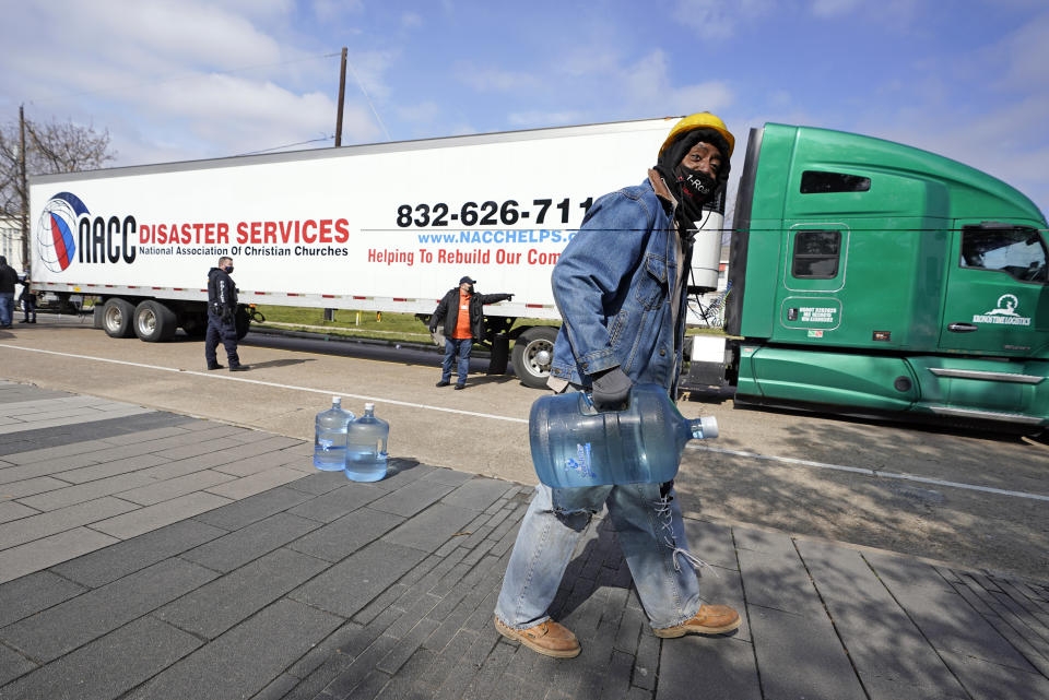 James White carries a jug of donated water from a distribution site, Thursday, Feb. 18, 2021, in Houston. Houston and several surrounding cities are under a boil water notice as many residents are still without running water in their homes. (AP Photo/David J. Phillip)