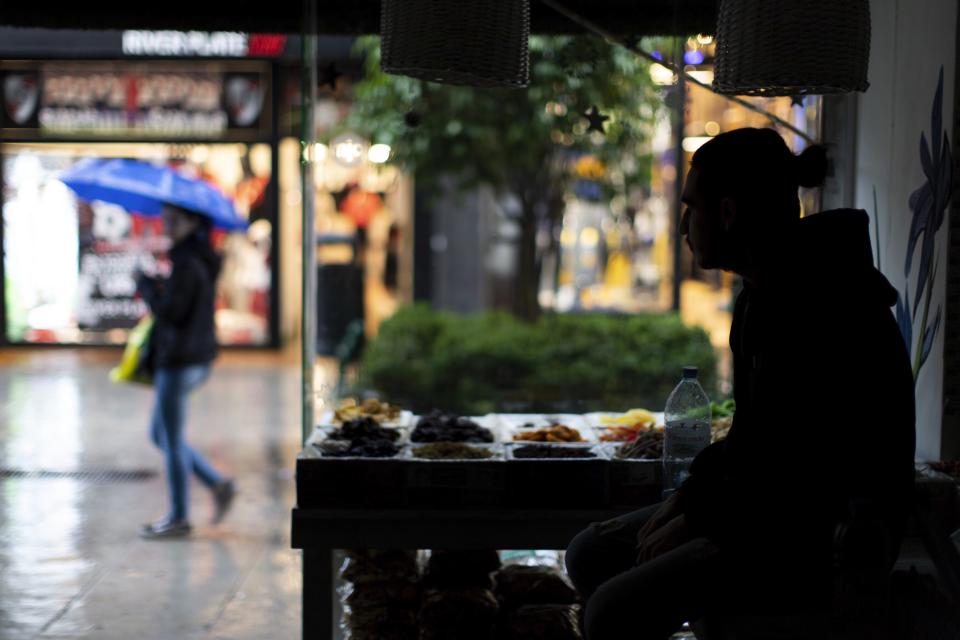 A pedestrian with an umbrella walks past a health food store which is still without electricity, in Buenos Aires, Argentina, Monday, June 17, 2019. As lights turned back on across Argentina, Uruguay and Paraguay after a massive blackout that hit tens of millions people, authorities were still largely in the dark about what caused the collapse of the interconnected grid and were tallying the damage from the unforeseen disaster. (AP Photo/Tomas F. Cuesta)