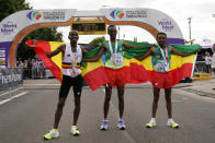 Gold medalist Tamirat Tola, of Ethiopia, center, stands with silver medalist Mosinet Geremew, of Ethiopia, right, and bronze medalist Bashir Abdi, of Belgium, after the men's marathon at the World Athletics Championships on Sunday, July 17, 2022, in Eugene, Ore. (AP Photo/Gregory Bull)