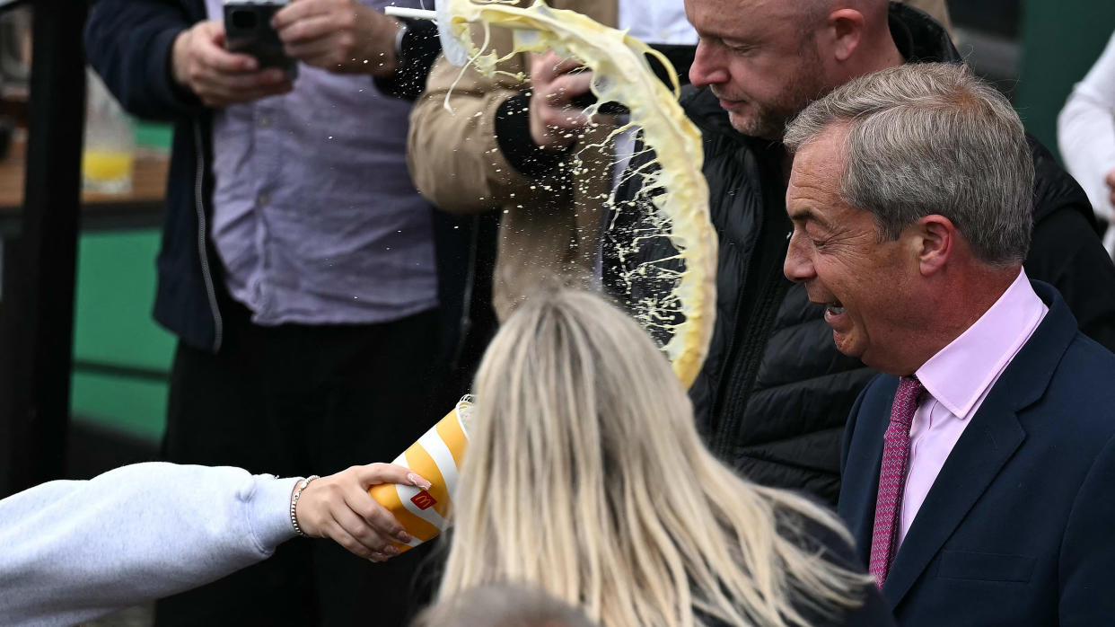 A person throws the contents of a drinks cup in the face of newly appointed leader of Britain's right-wing populist party, Reform UK, and the party's parliamentary candidate for Clacton, Nigel Farage, during his general election campaign launch in Clacton-on-Sea, eastern England, on June 4, 2024.