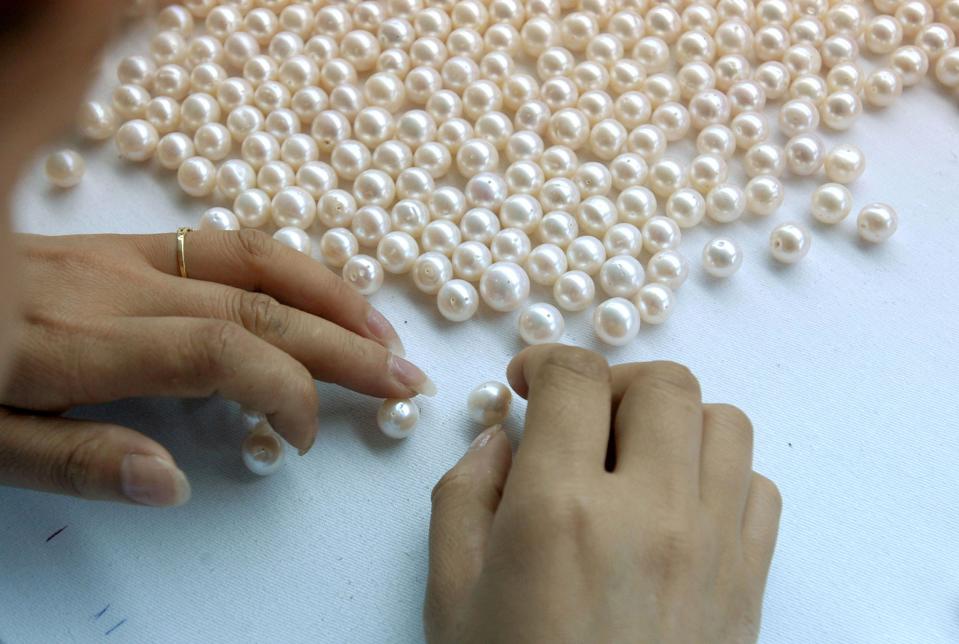 A worker classifies pearls.