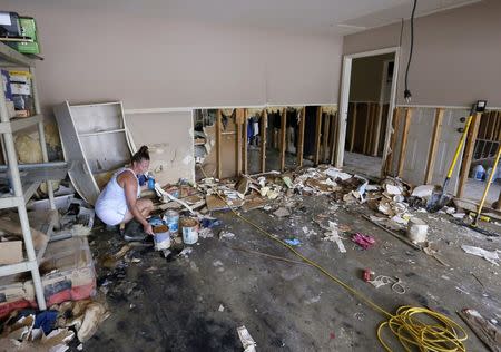 Sheryl Howard tries to salvage cans of paint in her flood damaged garage at the South Point subdivision in Denham Springs, Louisiana, U.S., August 22, 2016. REUTERS/Jonathan Bachman