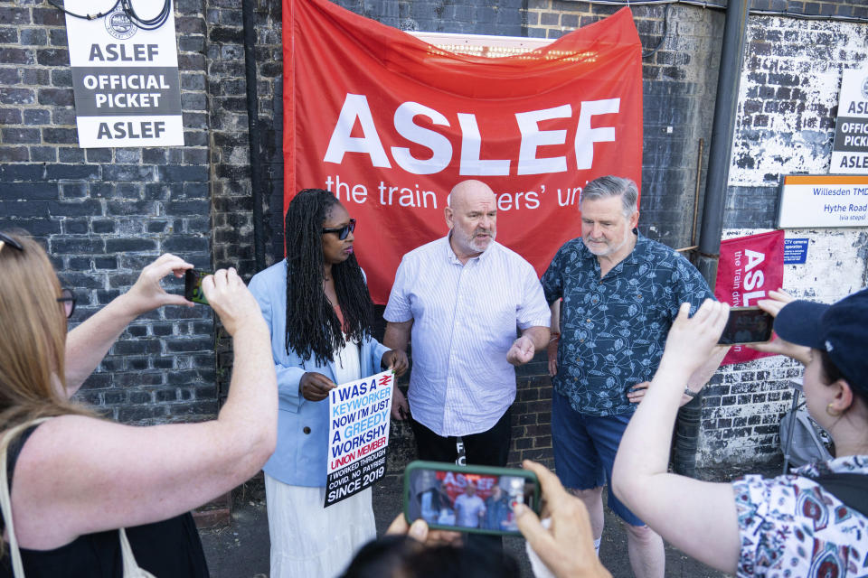Aslef General Secretary Mick Whelan,centre, speaks to the media alongside Labour MPs Dawn Butler and Barry Gardiner at a picket line at Willesden Junction station as members of the drivers union at nine train operators walk out for 24 hours over pay, in London, Saturday, Aug. 13, 2022. Thousands of U.K. train drivers walked off the job Saturday in a strike over jobs, pay and conditions, scuppering services across much of the country. It's the latest in a spreading series of strikes by British workers seeking substantial raises to offset soaring prices for food and fuel. (Dominic Lipinski/PA via AP)