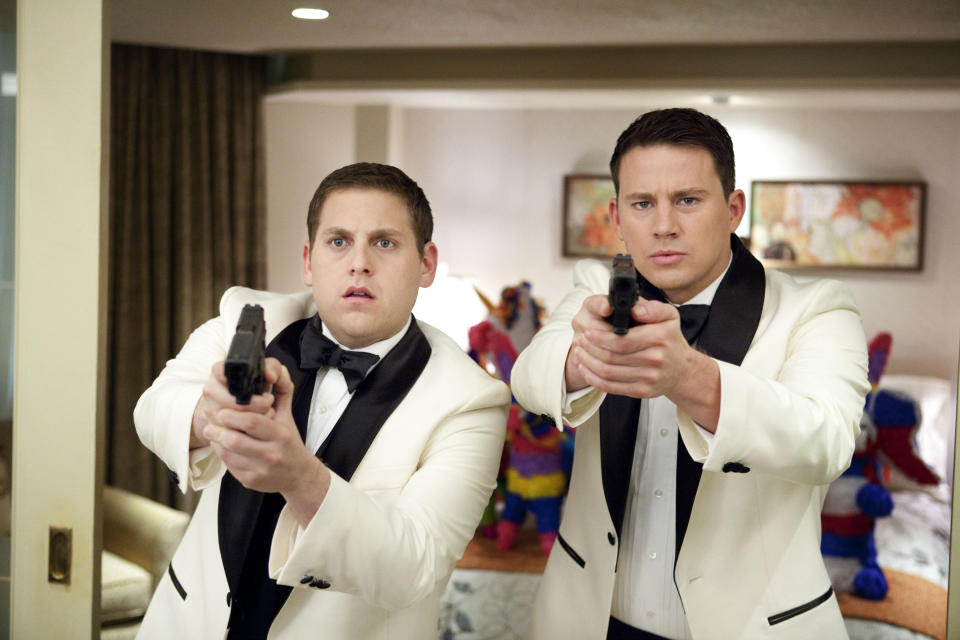 Jonah Hill and Channing Tatum, dressed in white tuxedos, holding guns in a scene from "21 Jump Street"