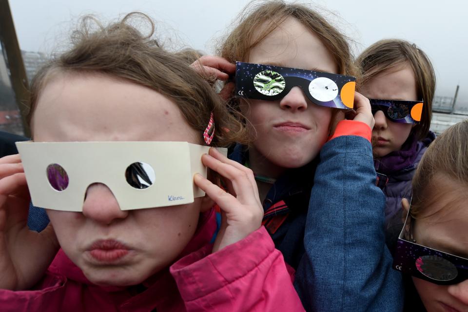 <p>Girsl use protective glasses to catch a glimpse of a solar eclipse as they stand in front of the observatory’s cupola on the roof of the university of applied sciences in Kiel, northern Germany, on March 20, 2015. (Photo: Carsten Rehder/AFP/Getty Images) </p>