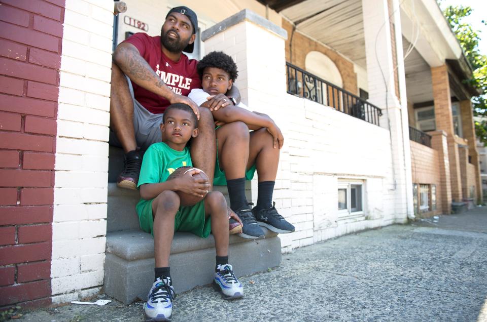 In this photo from 2019, Fran Brown, top, a Camden native who became one of the best college football recruiters in the country and is now the co-defensive coordinator and cornerbacks coach at Temple University, sits with his sons Brayden, left, and Frannie, right, as they visit the home on Morton Street in Camden where Brown once lived.