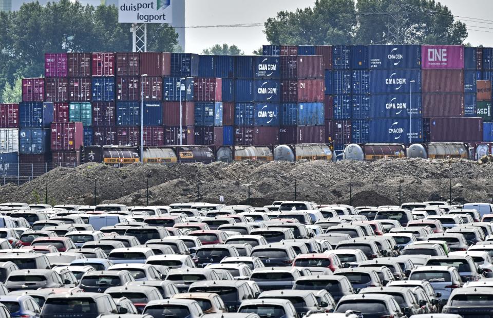 FILE - In thisJune 3, 2020 file photo, new cars are stored in front of containers at the 'logport' (logistic port) in Duisburg, Germany. Germany’s leading economic institutes has downgraded their forecast for Europe’s biggest economy saying it is still shaped by the impact of the coronavirus pandemic and that global supply bottlenecks also hamper the country’s recovery. (AP Photo/Martin Meissner)