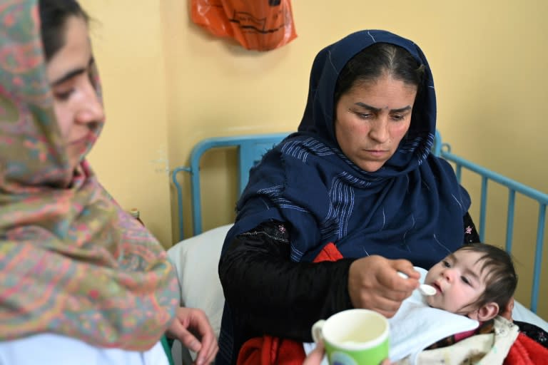 Samira (g), infirmière du service de malnutrition de l'hôpital de Baharak, donne du lait à la cuillère à une enfant, le 26 février 2024 dans la province du Badakhshan, en Afghanistan (Susannah WALDEN)