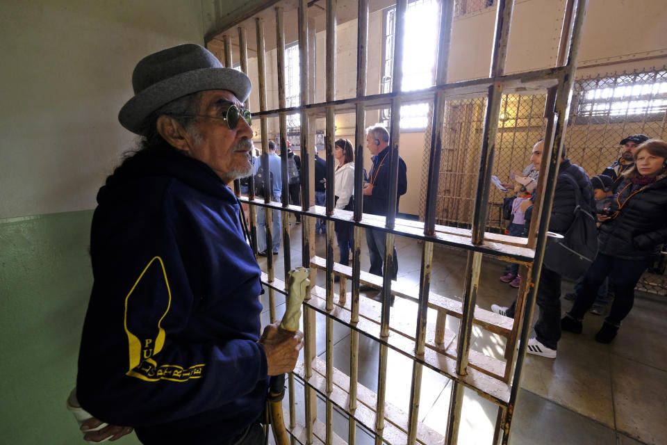 In this photo taken Tuesday, Nov. 12, 2019, Eloy Martinez, who took part in the Native American occupation of Alcatraz 50 years earlier, stands in the cell that he used to sleep in and looks out at tourists visiting the island in San Francisco. The week of Nov. 18, 2019, marks 50 years since the beginning of a months-long Native American occupation at Alcatraz Island in the San Francisco Bay. The demonstration by dozens of tribal members had lasting effects for tribes, raising awareness of life on and off reservations, galvanizing activists and spurring a shift in federal policy toward self-determination. (AP Photo/Eric Risberg)