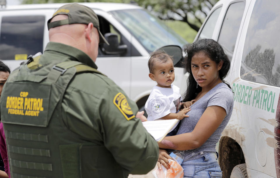 FILE - In this June 25, 2018, file photo, a mother migrating from Honduras holds her 1-year-old child as surrendering to U.S. Border Patrol agents after illegally crossing the border near McAllen, Texas. The women paid a smuggler to get them across the river. Once agents spotted the smuggler, he retreated to Mexico and the women surrendered to officials. Despite calls from some liberal Democrats to eliminate the Immigration and Customs Enforcement, most Democrats show little appetite for abolishing the agency at the center of the drama over immigrant children separated from their parents this summer. (AP Photo/David J. Phillip, File)