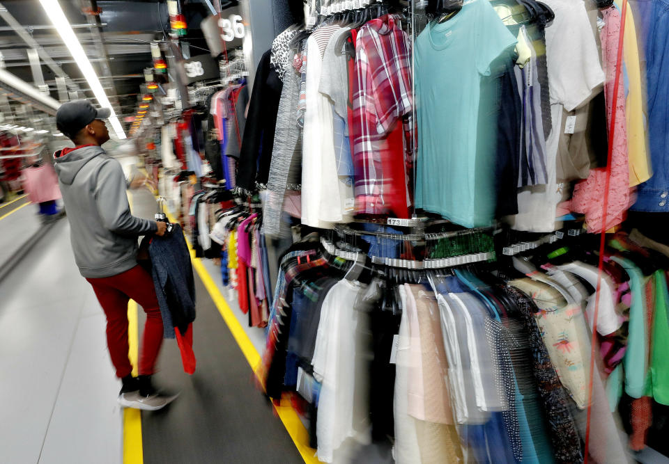 FILE - Willie Walton hangs clothing on a three-tiered conveyor system at the ThredUp sorting facility in Phoenix on March 12, 2019. A wardrobe purge is on for some as vaccinations have taken hold, restrictions have lifted and offices reopen or finalize plans to do so. The primary beneficiaries are secondhand clothing marketplaces, and brick-and-mortar donation spots. (AP Photo/Matt York, File)