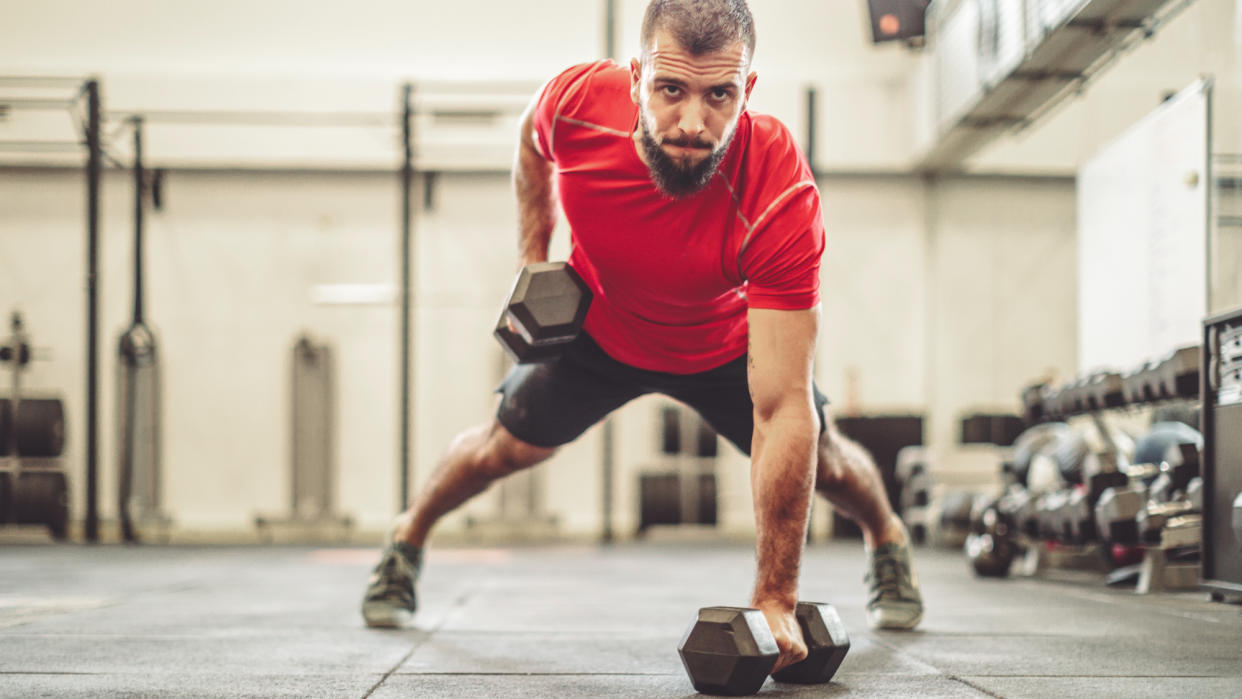  Man performing dumbbell renegade rows 