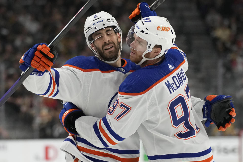 Edmonton Oilers center Connor McDavid, right, embraces defenseman Evan Bouchard (2) after Bouchard scored against the Vegas Golden Knights during the first period of Game 2 of an NHL hockey Stanley Cup second-round playoff series Saturday, May 6, 2023, in Las Vegas. (AP Photo/John Locher)