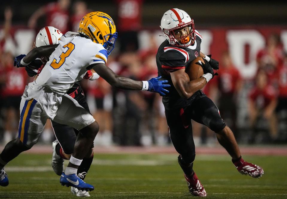 Center Grove Trojans Jalen Thomeson (1) rushes the ball past Carmel Greyhounds Christian Peterson (3) on Friday, August 26, 2022 at Center Grove High School in Greenwood. The Center Grove Trojans defeated the Carmel Greyhounds, 31-27, making this their 30th straight win. 