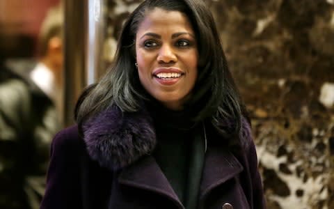 Omarosa Manigault smiles at reporters as she walks through the lobby of Trump Tower in New York - Credit: AP