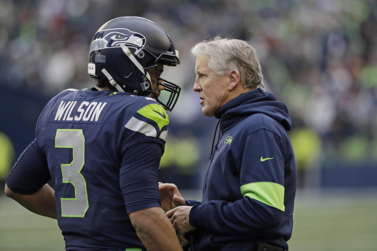 Seattle Seahawks head coach Pete Carroll, right, talks with quarterback Russell Wilson, left, during the first half of an NFL football game against the Arizona Cardinals, Sunday, Dec. 22, 2019, in Seattle. (AP Photo/Elaine Thompson)