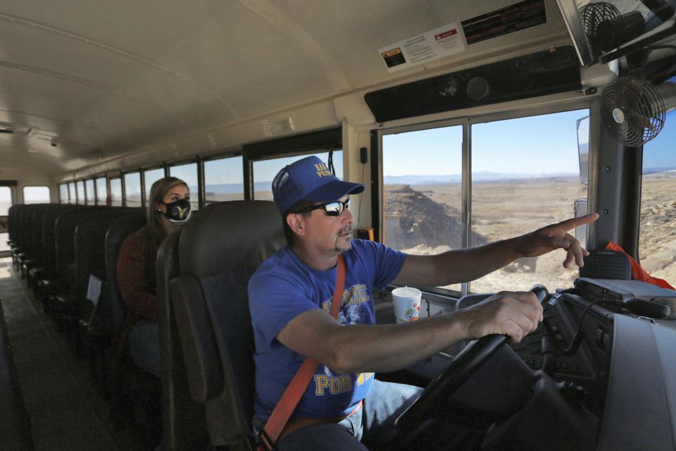 School bus driver by Kelly Maestas travels along a dirt road, with social worker Victoria Dominguez, outside Cuba, N.M., Oct. 19, 2020. The switch to remote learning in rural New Mexico has left some students profoundly isolated — cut off from others and the grid by sheer distance. The school system is sending school buses to students’ far-flung homes to bring them assignments, meals and a little human contact. (AP Photo/Cedar Attanasio)