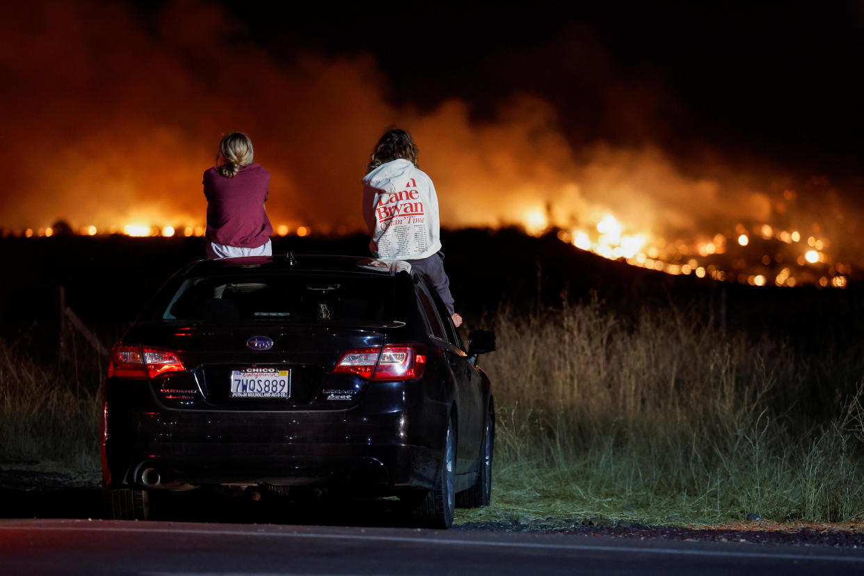 Lily Moore and Megan Panighetti watch the Park Fire burning as they sit on top of a car in Chico, California, on July 25, 2024. / Credit: Reuters/Fred Greaves